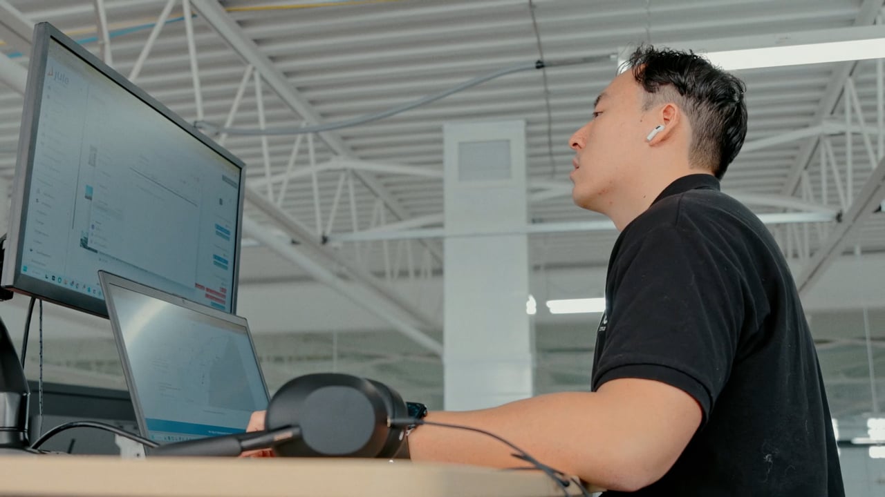 A Jule Power customer service agent at his desk, headset on, in the company&rsquo;s open-plan office