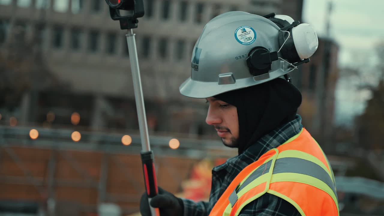 A surveyor in hard hat and hi-vis working with survey equipment on a Kenaidan site